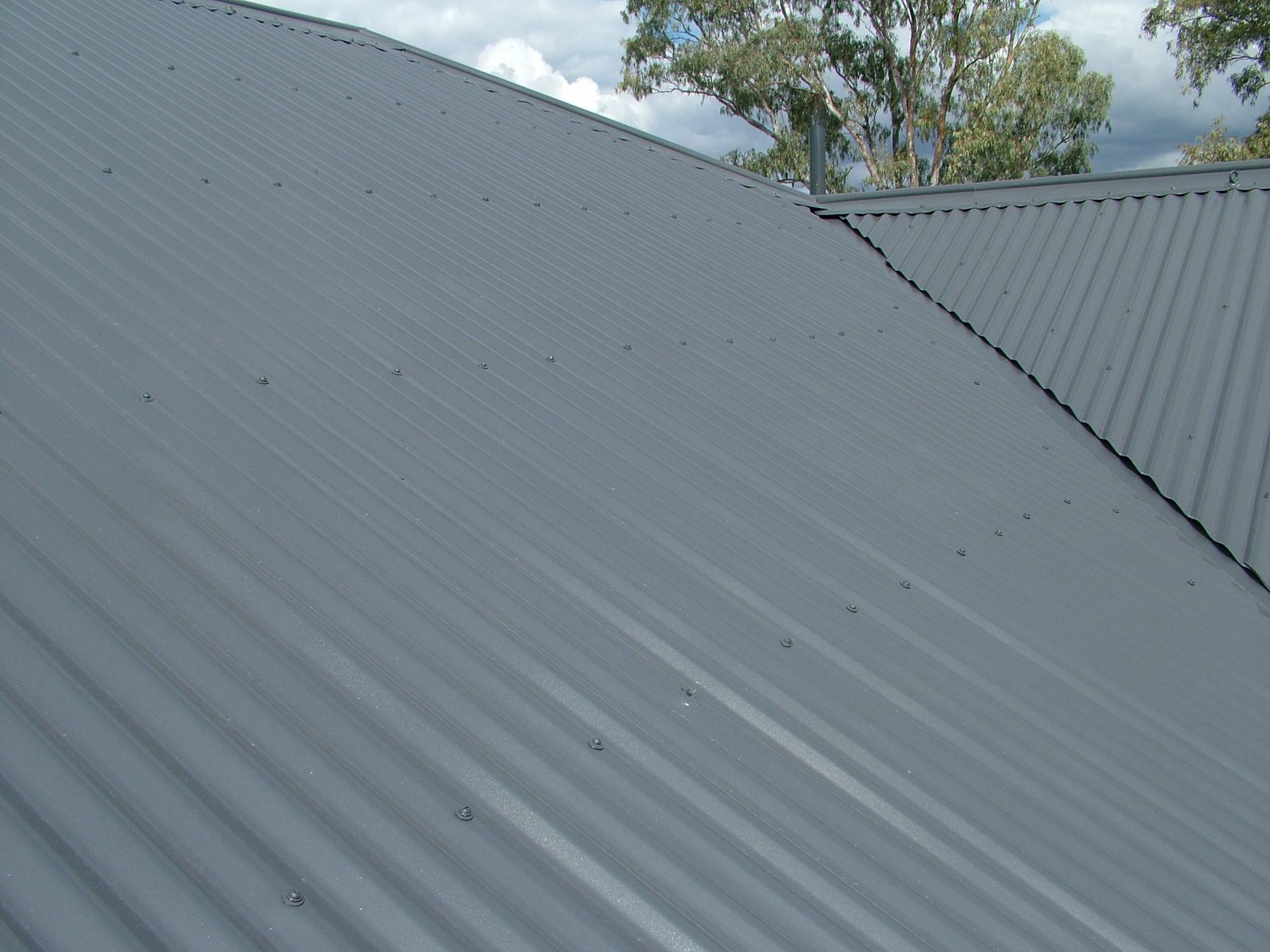 Restored metal roof ridge under clear sky on a Hunter region home