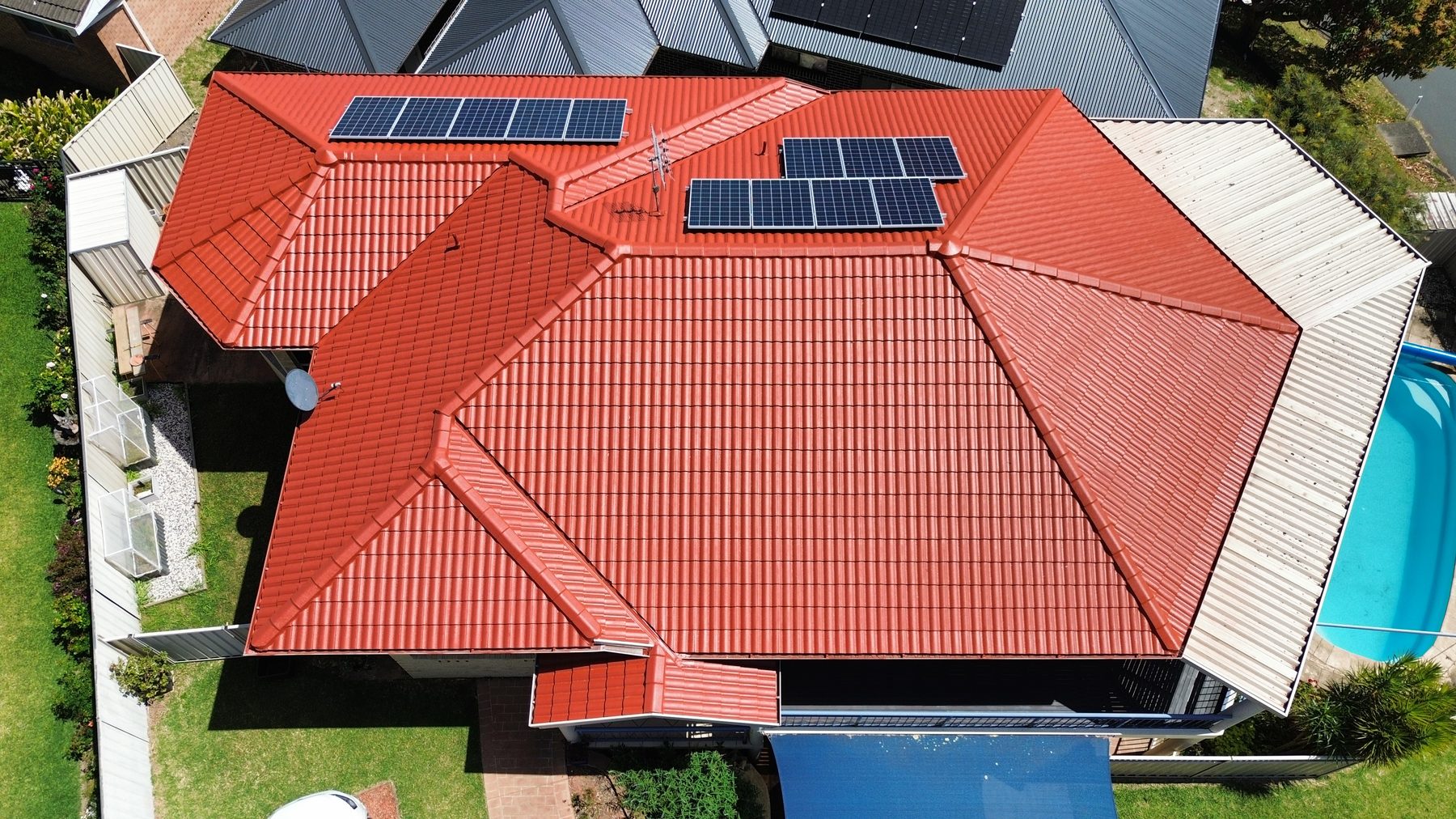 Aerial view of a terracotta tile roof with solar panels after roof painting