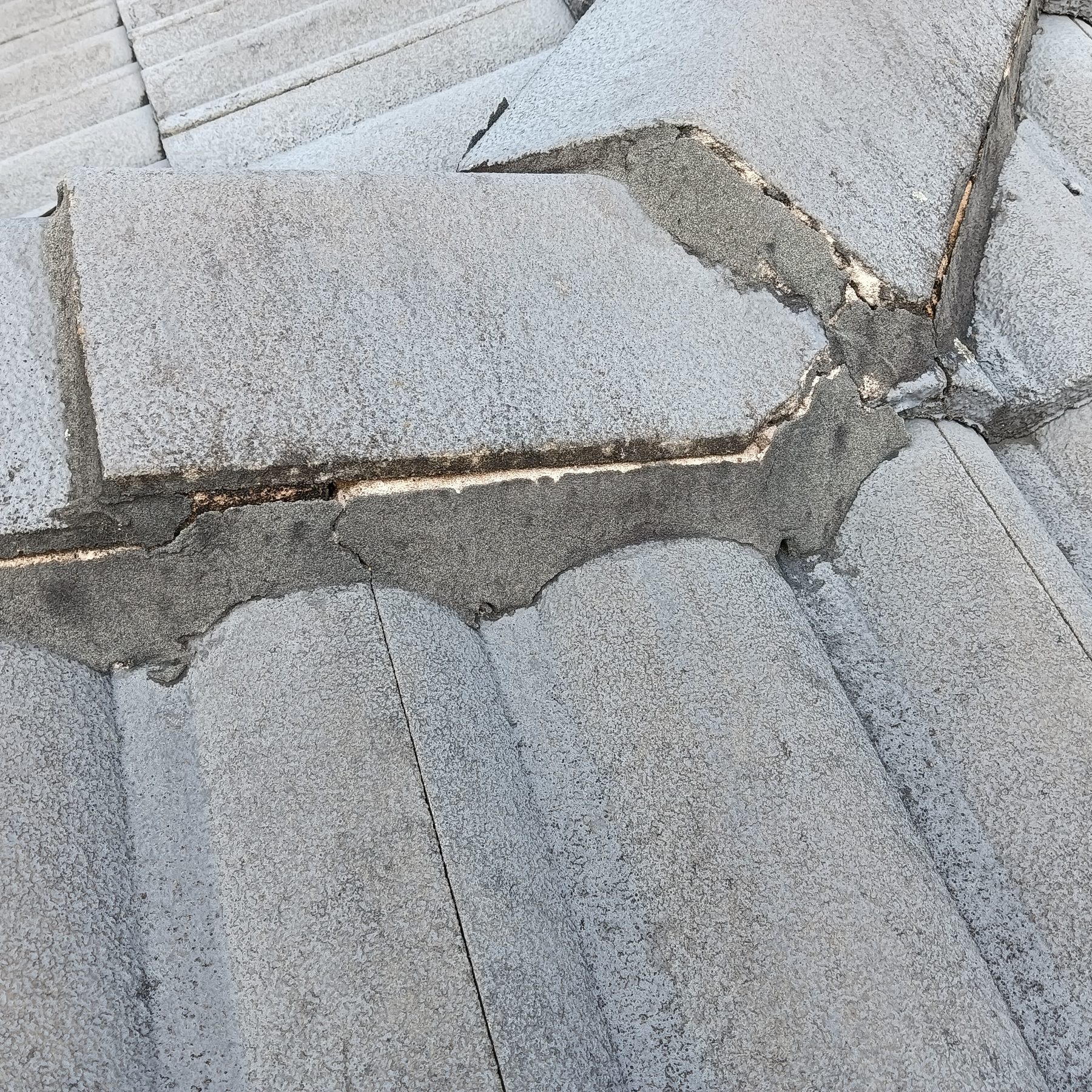 Split roof tile and failed bedding exposed during Central Coast roof repairs