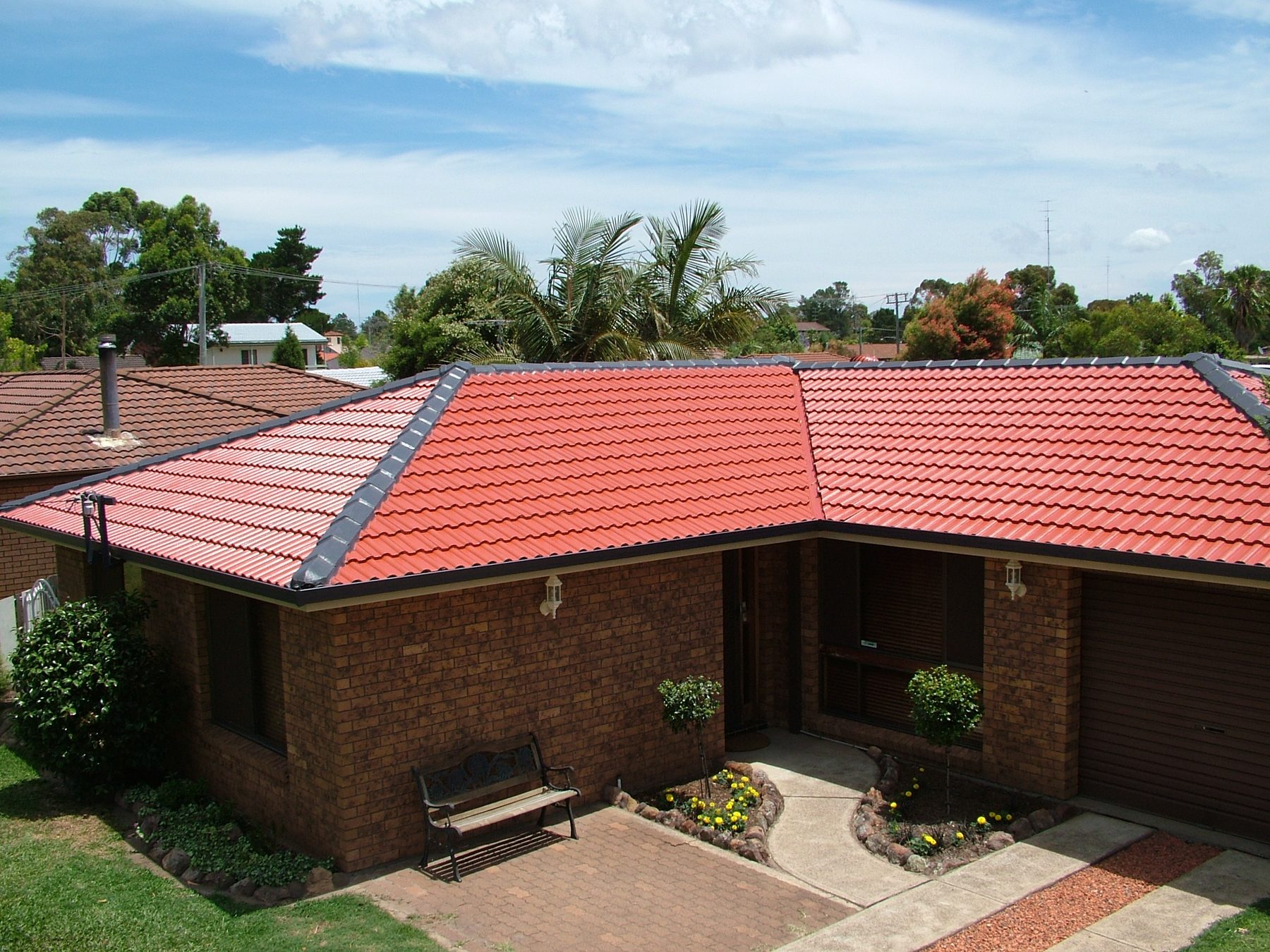 Brick home with a freshly restored red tile roof completed by Roof Restoration Masters