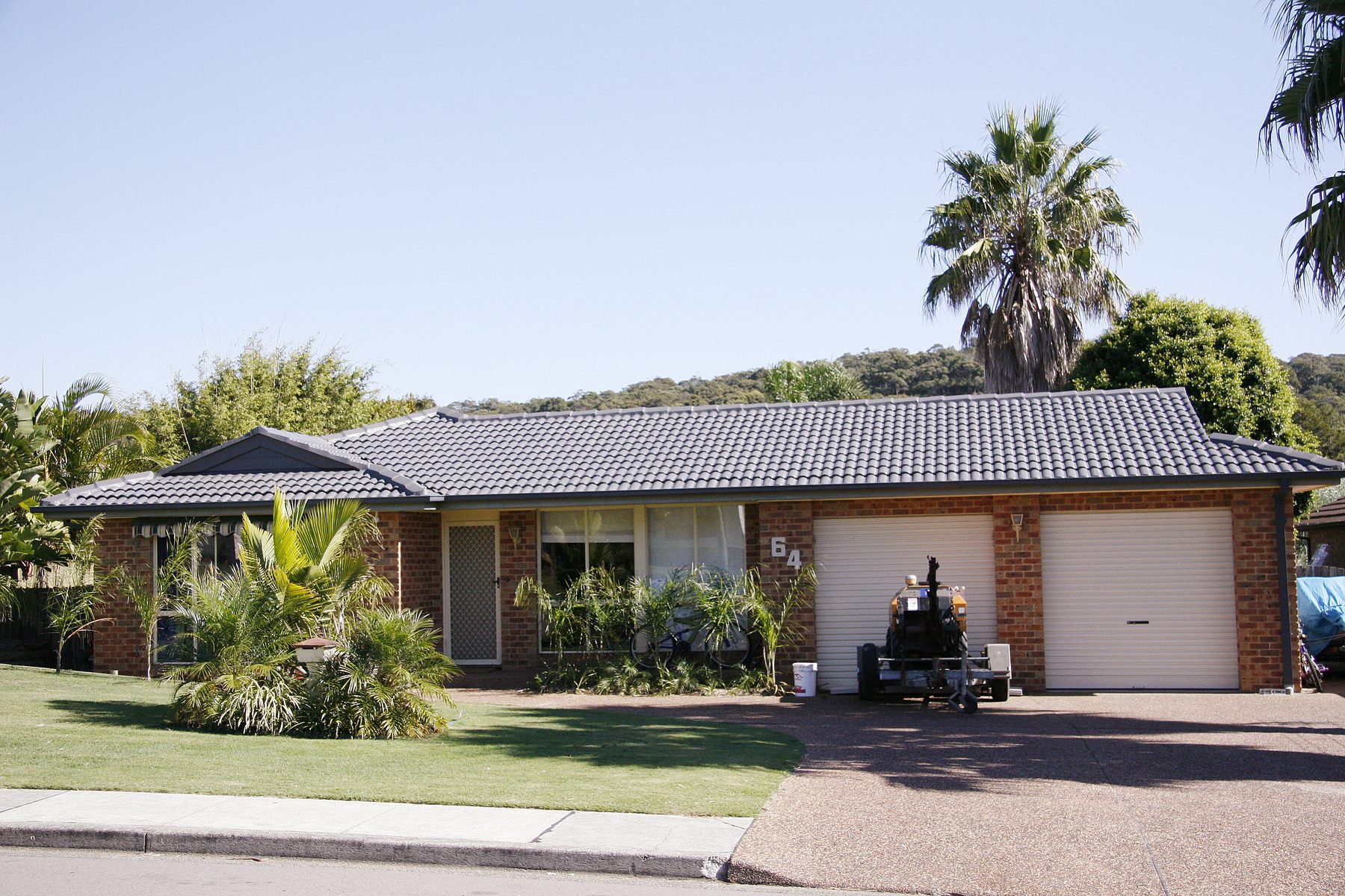 Street view of a brick home with a restored tile roof in the Hunter region